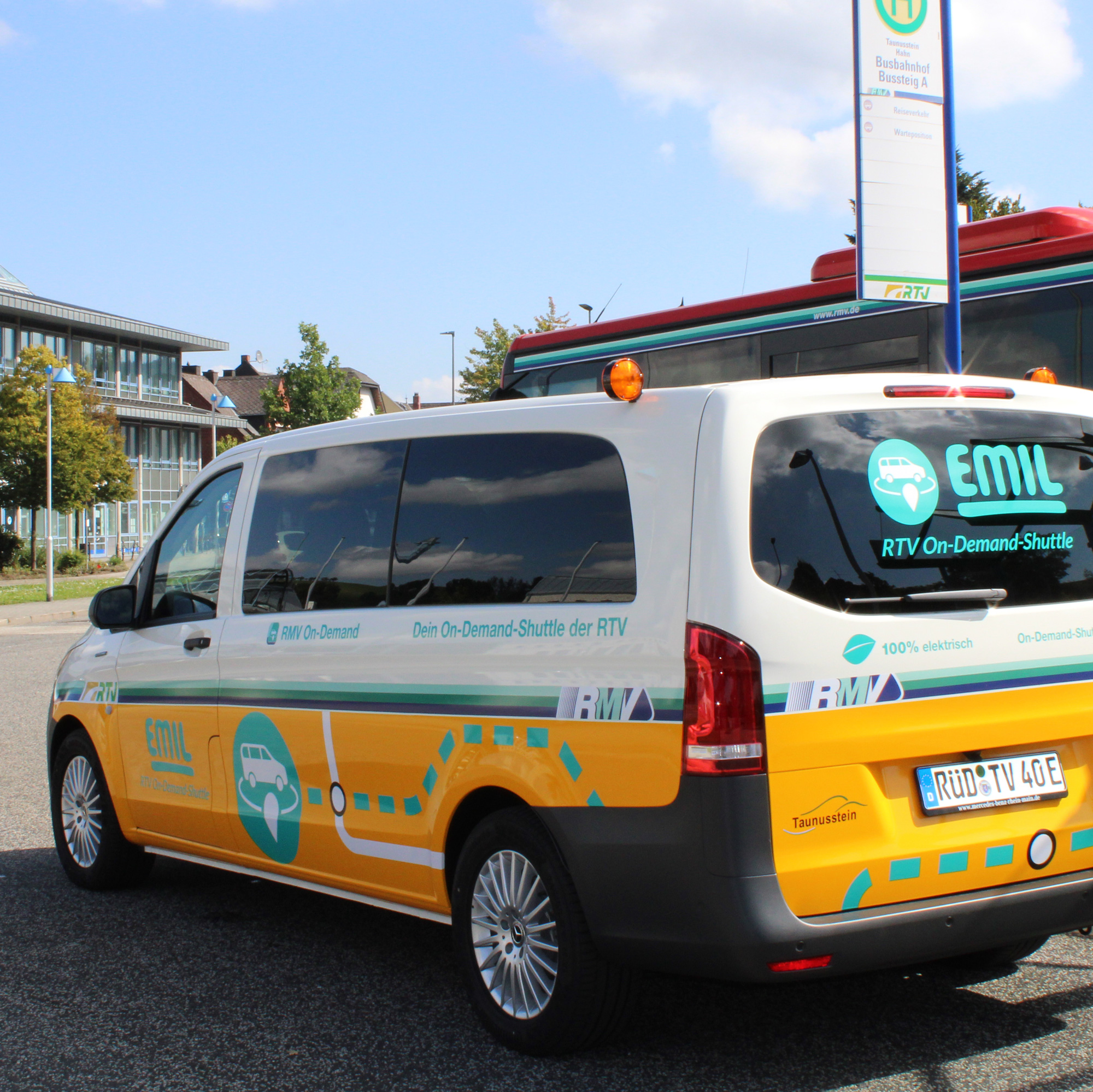 Das elektrische On-Demand-Shuttle „EMIL“ der Rheingau-Taunus-Verkehrsgesellschaft steht am Zentralen Ortsbahnhof Taunusstein. Das gelb-weiße Fahrzeug trägt das RTV-Branding und ist mit Hinweisen auf den emissionsfreien Betrieb beschriftet.